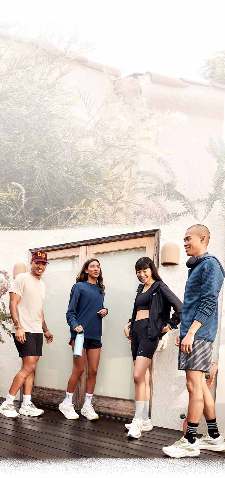 Four people wearing Brooks gear, standing and talking against a neutral-coloured background